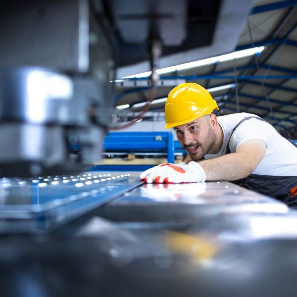 factory worker protective uniform hardhat operating industrial machine production line